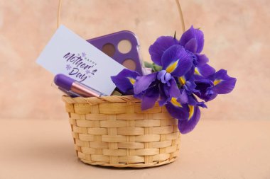 Bej rengi grunge arka planda anneler günü için süsen çiçekleri, kartpostal ve kozmetik sepetleri.