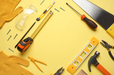 Sarı arkaplandaki inşaat araçlarından yapılmış çerçeve