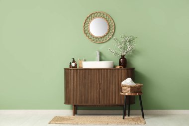 Dal dallı vazo ve banyonun içindeki yeşil duvarın yanındaki çekmecelerin üzerine lavabo.