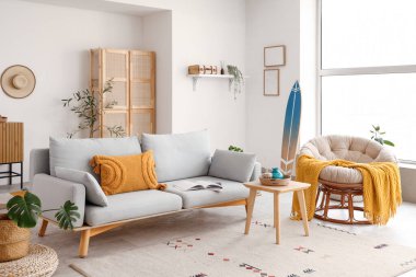 Sörf tahtası, kanepesi ve koltuğu olan bir oturma odası.