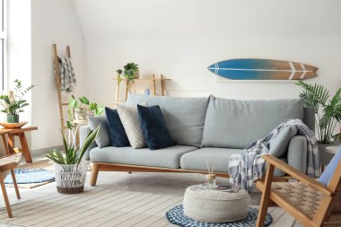 Sörf tahtası, kanepesi ve bitkileri olan bir oturma odası.