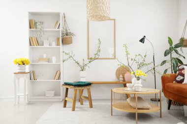 Kitap rafı, nergisleri ve çiçek açan vazolarla aydınlık oturma odasının içinde.