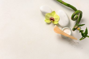 Işık arka planında kozmetik ürün kavanozu, spa taşları ve bambu sapıyla kompozisyon