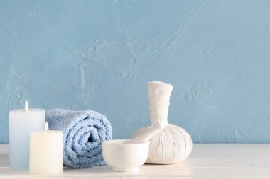 Renk duvarının yanındaki açık ahşap masada yanan mumlarla kaplıca aksesuarları.