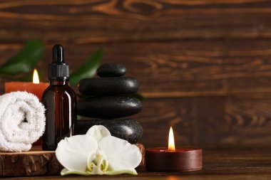 Kaliteli yağ, spa taşları, havlu ve yanan mumlarla ahşap masa.