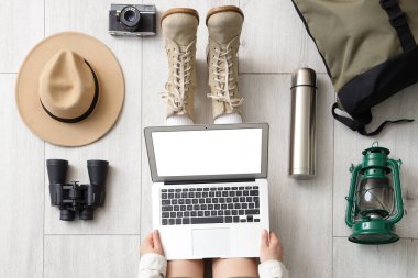 Diz üstü bilgisayarı ve aksesuarları olan kadın gezgin, ahşap zemin, üst görünüm