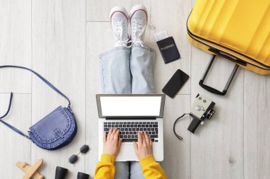 Diz üstü bilgisayarı ve seyahat aksesuarları kullanan kadın turist.