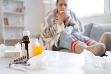 Evdeki hasta kadına karşı masasında mendil bulunan farklı grip ilaçları.