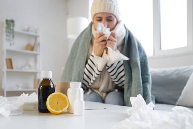 Evde hapşıran hasta kadınlara karşı masada limon bulunan farklı grip ilaçları.
