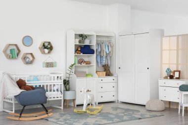 Bebek beşiği, dolabı ve sallanan koltuğu olan bir kreş.