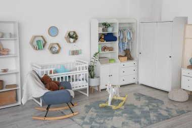 Bebek beşiği, dolabı ve sallanan koltuğu olan bir kreş.