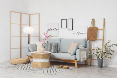 Aydınlık oturma odasının içinde kanepe, katlanan perde ve çiçekli vazolar