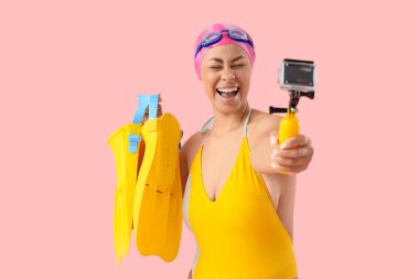 Yüzgeçli Afro-Amerikalı bir yüzücü pembe arka planda video çekiyor.