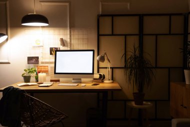 Karanlık ofis içinde boş bilgisayar monitörü ve parlayan lambası olan işyeri