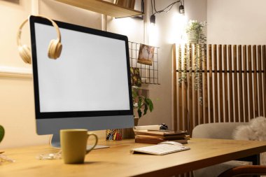 Geceleri ofiste masasında kulaklık olan boş bilgisayar monitörü.