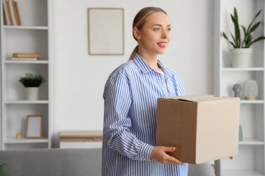 Evde paket kutusu olan genç bir kadın.