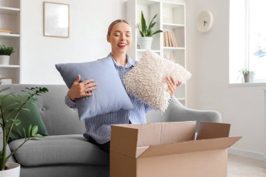 Evdeki kutudan yastık alan genç bir kadın.