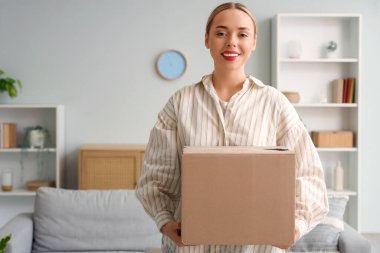 Evde paket kutusu olan genç bir kadın.