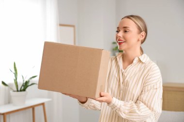 Evde paket kutusu olan genç bir kadın.