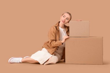 Bej arka planda kutuları olan genç bir kadın.