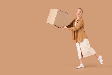 Bej arka planda bir paket kutusu olan genç bir kadın.