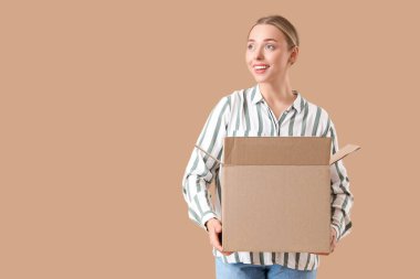 Bej arka planda açık paket kutusu olan genç bir kadın.
