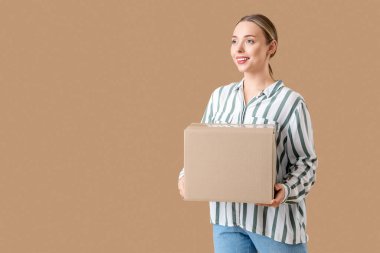 Bej arka planda bir paket kutusu olan genç bir kadın.