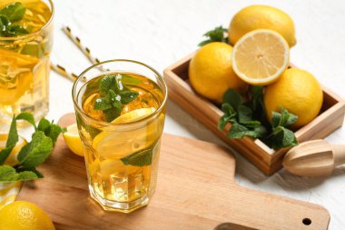 Beyaz arka planda nane ve turunçgil meyveli limonlu buzlu çay, yakın plan.