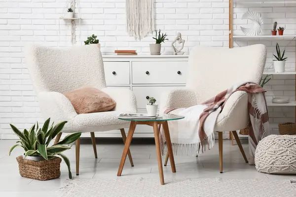 Oturma odasının içinde koltuklar, masa ve yeşil bitkiler