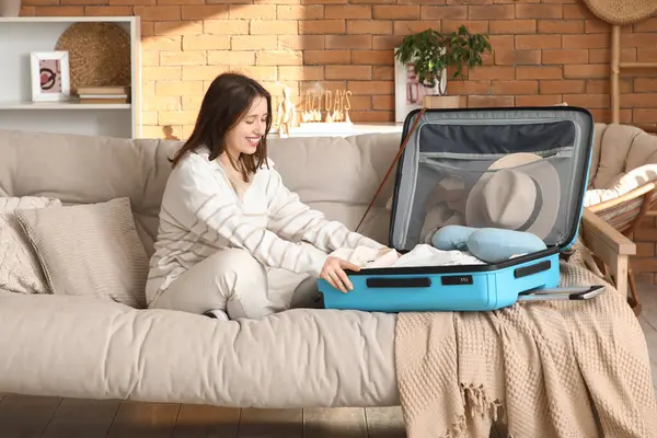 Güzel genç bir kadın bavulunu evde kıyafetleriyle açıyor.