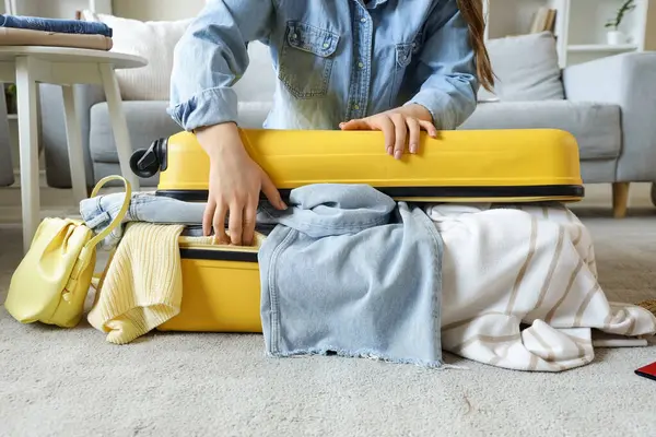 Bayan turist valizini evde kapatmaya çalışıyor.