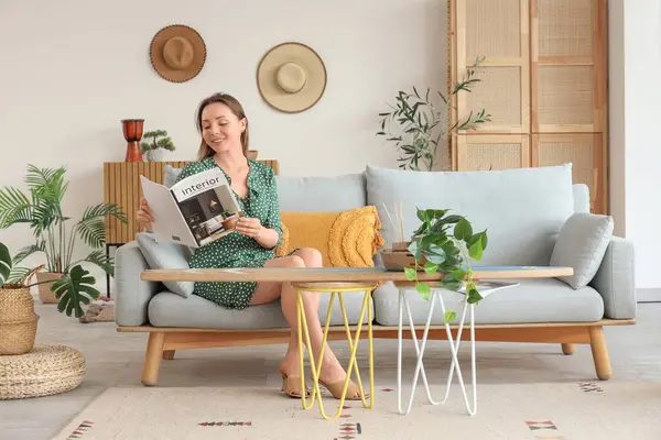 Oturma odasında sörf tahtasıyla kanepede dergi okuyan genç bir kadın.