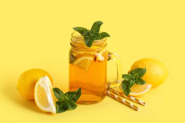 Sarı arka planda nane ve turunçgil meyveli limon buzlu çay.