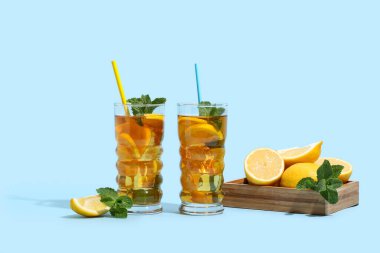 Mavi arka planda nane ve turunçgil meyveli limonlu buzlu çay.