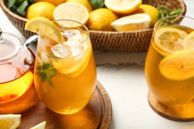 Beyaz arka planda nane ve turunçgil meyveli limonlu buzlu çay, yakın plan.