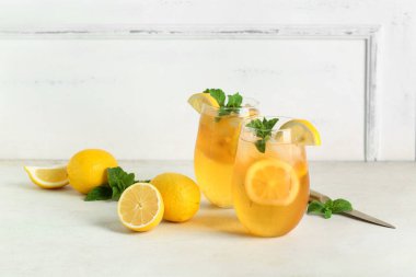 Beyaz arka planda nane ve turunçgil meyveli limonlu buzlu çay.