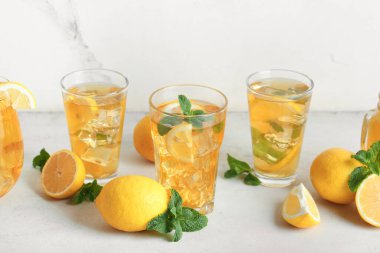 Beyaz arka planda nane ve turunçgil meyveli limonlu buzlu çay.