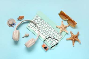Mavi arka planda kulaklıklı, güneş gözlüklü ve plaj dekorlu bilgisayar klavyesi