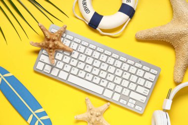 Kulaklıklı bilgisayar klavyesi ve sarı arka planda plaj dekoru.
