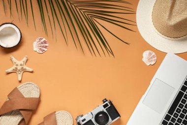 Kamera, parmak arası terlik ve turuncu arka planda plaj dekorundan yapılmış bir çerçeve.