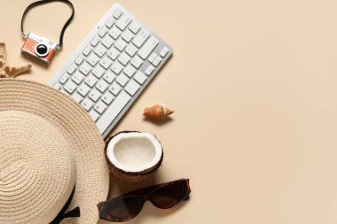 Bej arka planda kamera ve plaj aksesuarları olan bilgisayar klavyesi