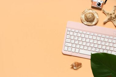 Kamera ve turuncu arka planda plaj dekoru olan bilgisayar klavyesi