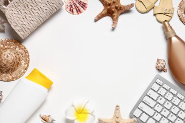 Beyaz arkaplanda güneş kremi ve plaj dekoru olan bilgisayar klavyesinden yapılmış çerçeve
