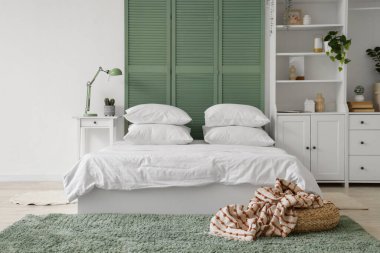 Beyaz çarşaflı, beyaz perdeli ve dolabı olan ışık odasının içinde.