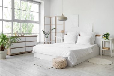 Beyaz çarşaflı, beyaz perdeli ve bitkilerle aydınlatma odasının içinde.