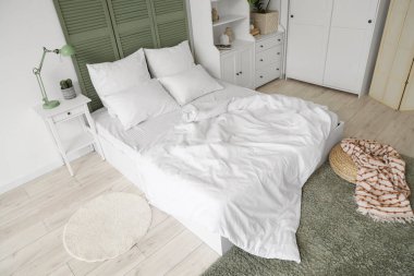 Beyaz çarşaflı, beyaz perdeli ve dolabı olan ışık odasının içinde.