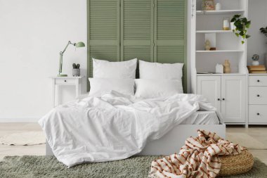 Beyaz çarşaflı, beyaz perdeli ve dolabı olan ışık odasının içinde.