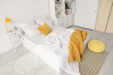 Yatak ve dolapta beyaz çarşaf olan aydınlatma odasının içinde.