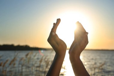 Gün batımında kadın elleri nehre karşı. Yaz gündönümü