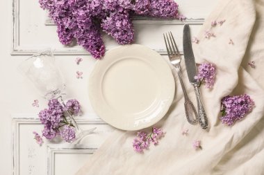 Beyaz arka planda leylak çiçekleri olan güzel bir masa.